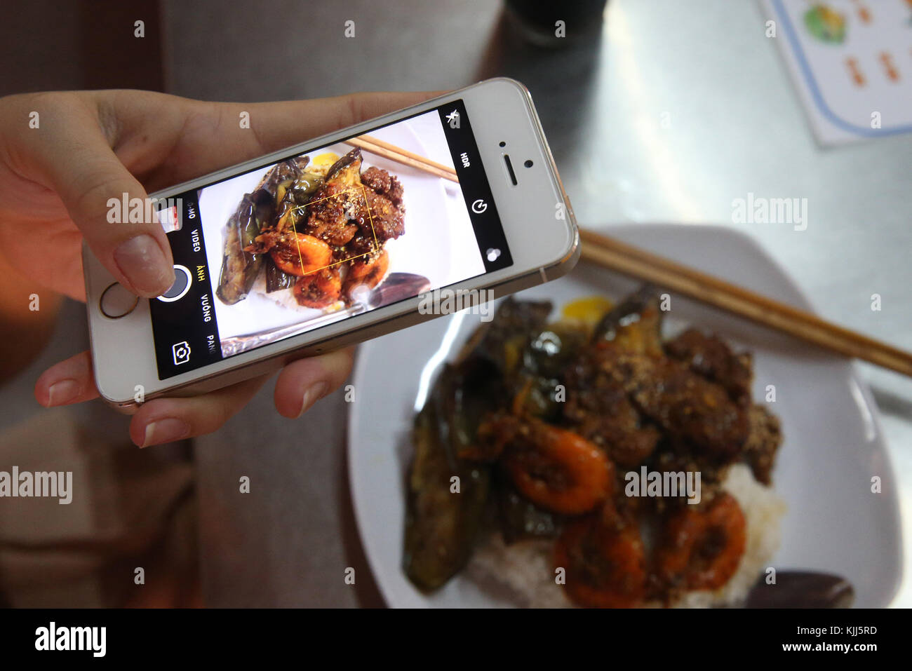 Femme à l'aide de son smartphone pour prendre une photo de son repas. Hoi An. Le Vietnam. Banque D'Images