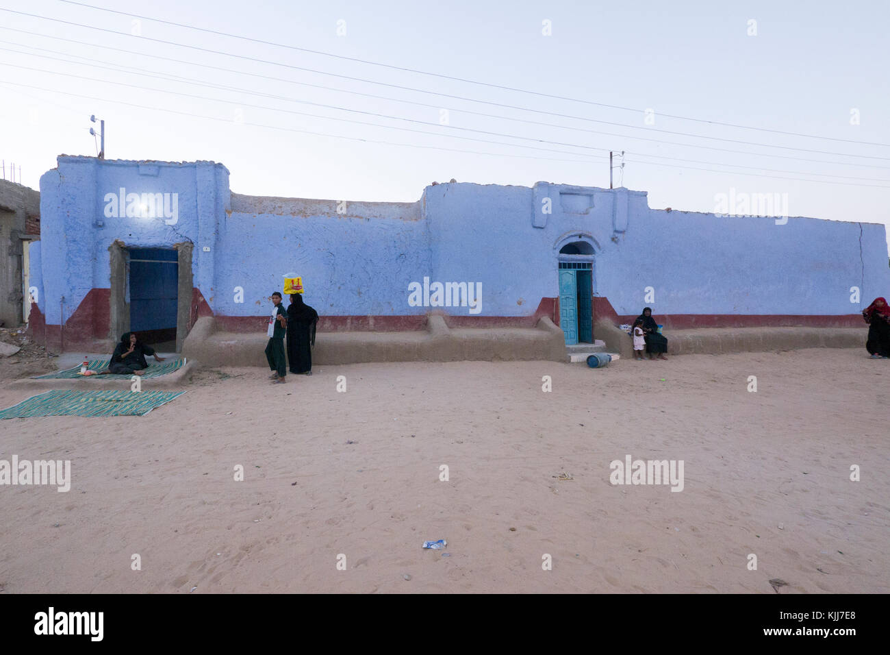 Les villageois, en suspens, à la tombée de l'extérieur de leurs maisons nubiennes bleu traditionnel dans un petit village sur les rives du Nil à Assouan, au sud de l'Égypte. Banque D'Images