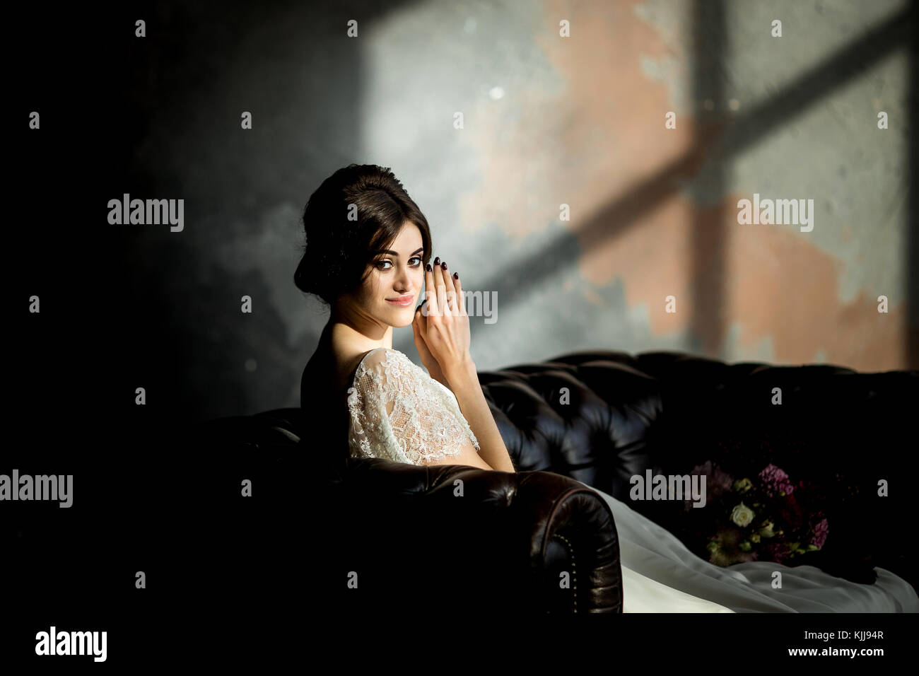 Belle robe de mariée assis sur une chaise à l'intérieur dans dark studio intérieur comme à la maison. Banque D'Images