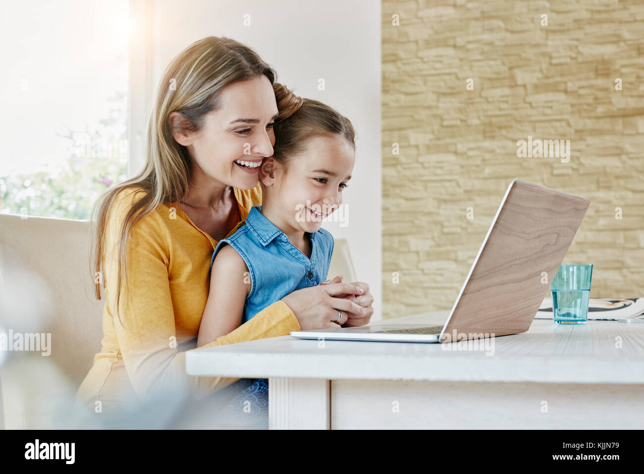Happy mother with daughter at home looking at laptop Banque D'Images
