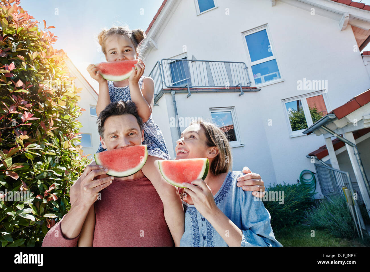 Portrait de famille heureuse avec des tranches de melon d'eau en face de leur maison Banque D'Images