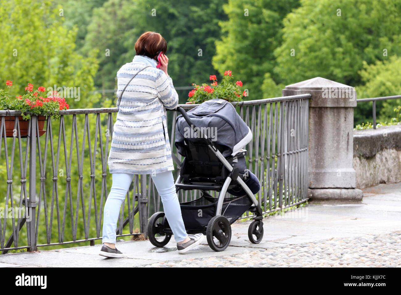 Jeune mère en utilisant son mobile dans la rue. L'Italie. Banque D'Images