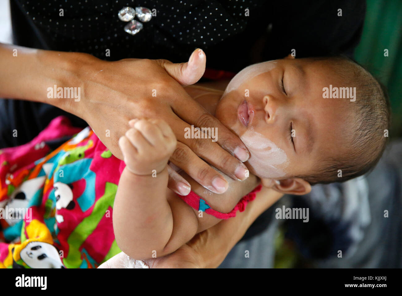 L'application mère coller sur son visage du bébé. Battambang. Le Cambodge. Banque D'Images