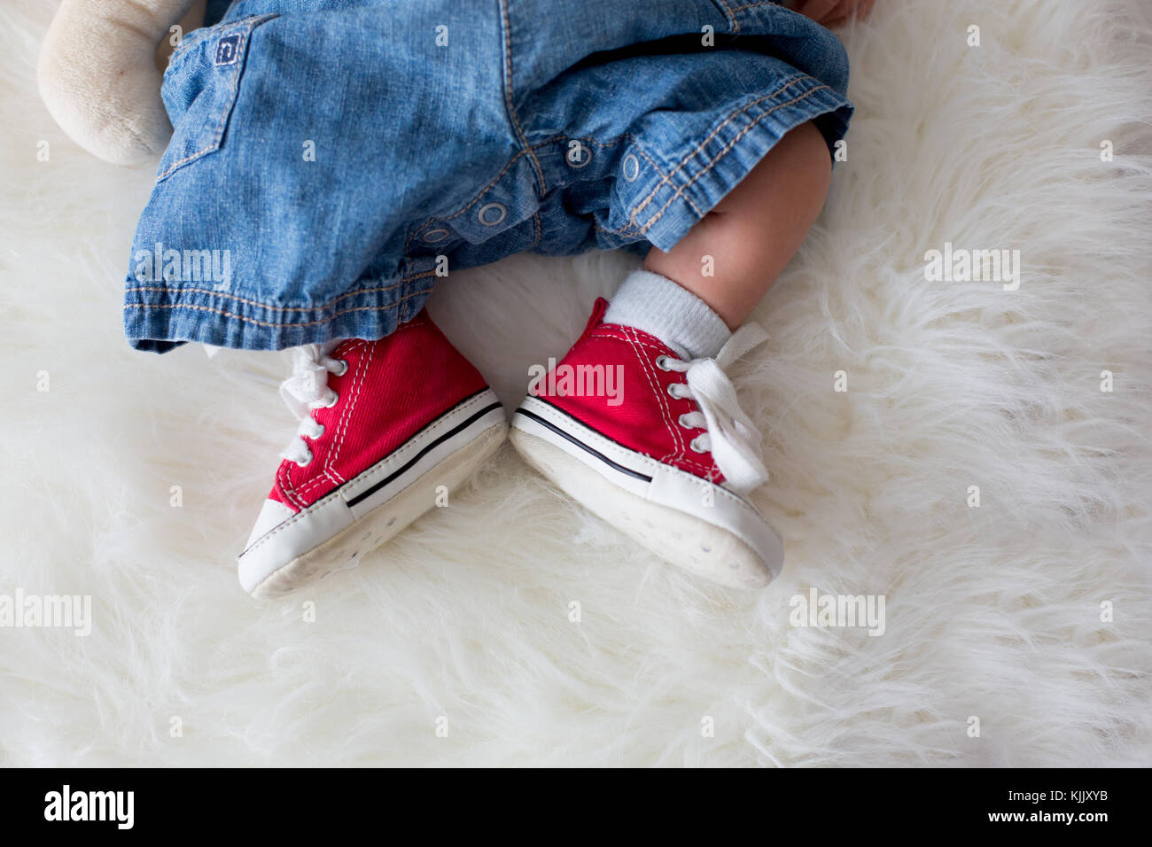 Rouge à la mode sneakers sur petit bébé nouveau-né bébé garçon garçons  pieds, portant des jeans et baskets Photo Stock - Alamy