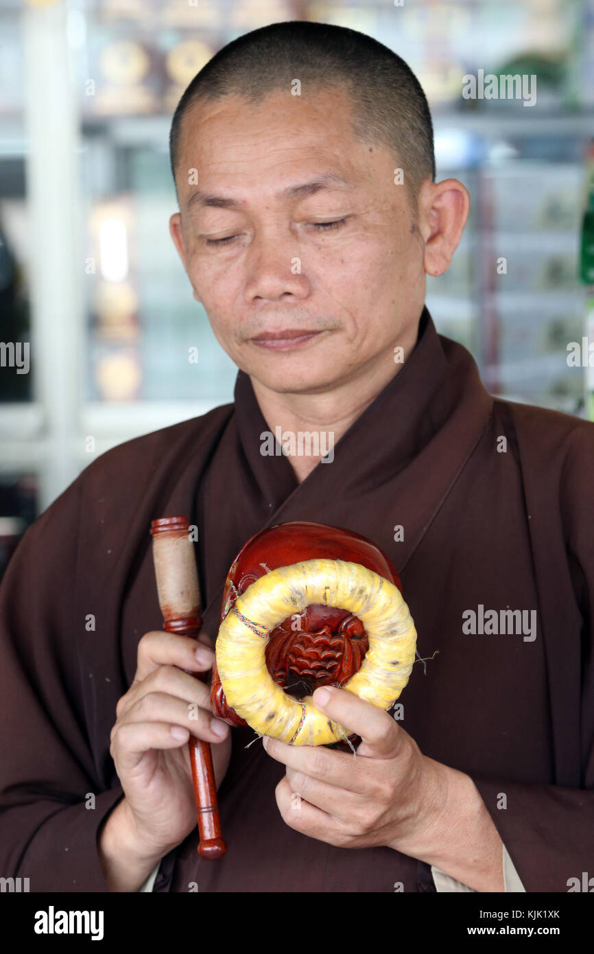Cérémonie bouddhiste. Monk jouant sur un poisson en bois (instrument à percussion). Danang. Le Vietnam. Banque D'Images