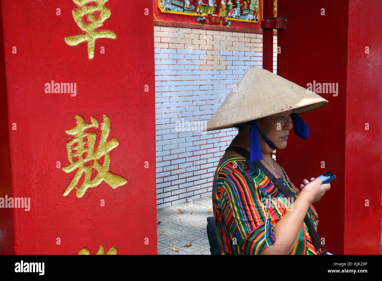 Caractères chinois sur pilier et vietnamienne avec smartphone. Ho Chi Minh Ville. Le Vietnam. Banque D'Images