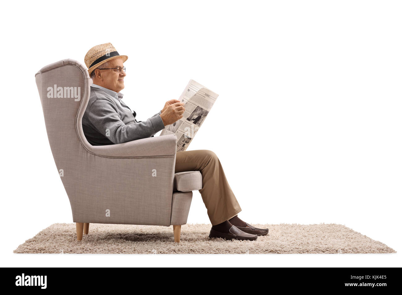 Homme mûr assis dans un fauteuil et lit un journal isolé sur fond blanc Banque D'Images