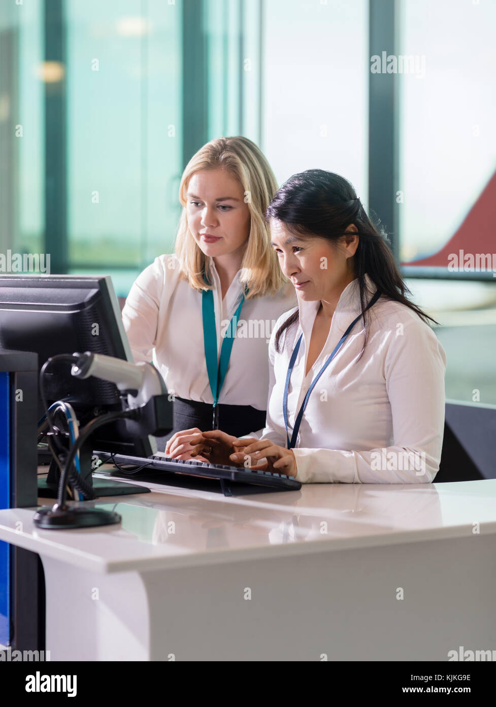 Le personnel au sol à l'aide des femmes multiethniques ordinateur à la réception à l'aéroport Banque D'Images