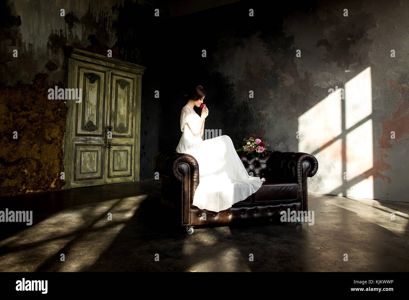 Belle robe de mariée assis sur une chaise à l'intérieur dans dark studio intérieur comme à la maison. Banque D'Images