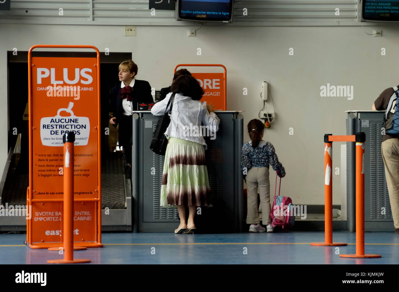 Les voyageurs de loisirs, d'une mère et de la jeune fille au Terminal3 easyJet guichets d'enregistrement avec 'pas de bagages à des restrictions de poids' signes en langue française Banque D'Images