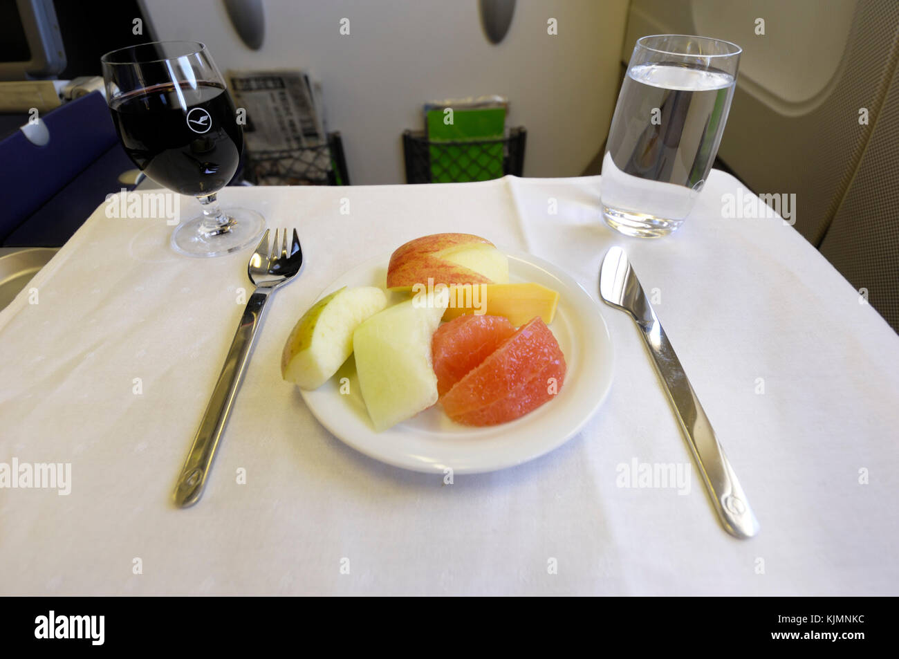 Repas de fruits frais avec fourchette et couteau couverts, avec des verres de vin rouge et de l'eau des boissons dans la cabine de classe affaires dans l'Airbus A340 Lufthansa Banque D'Images