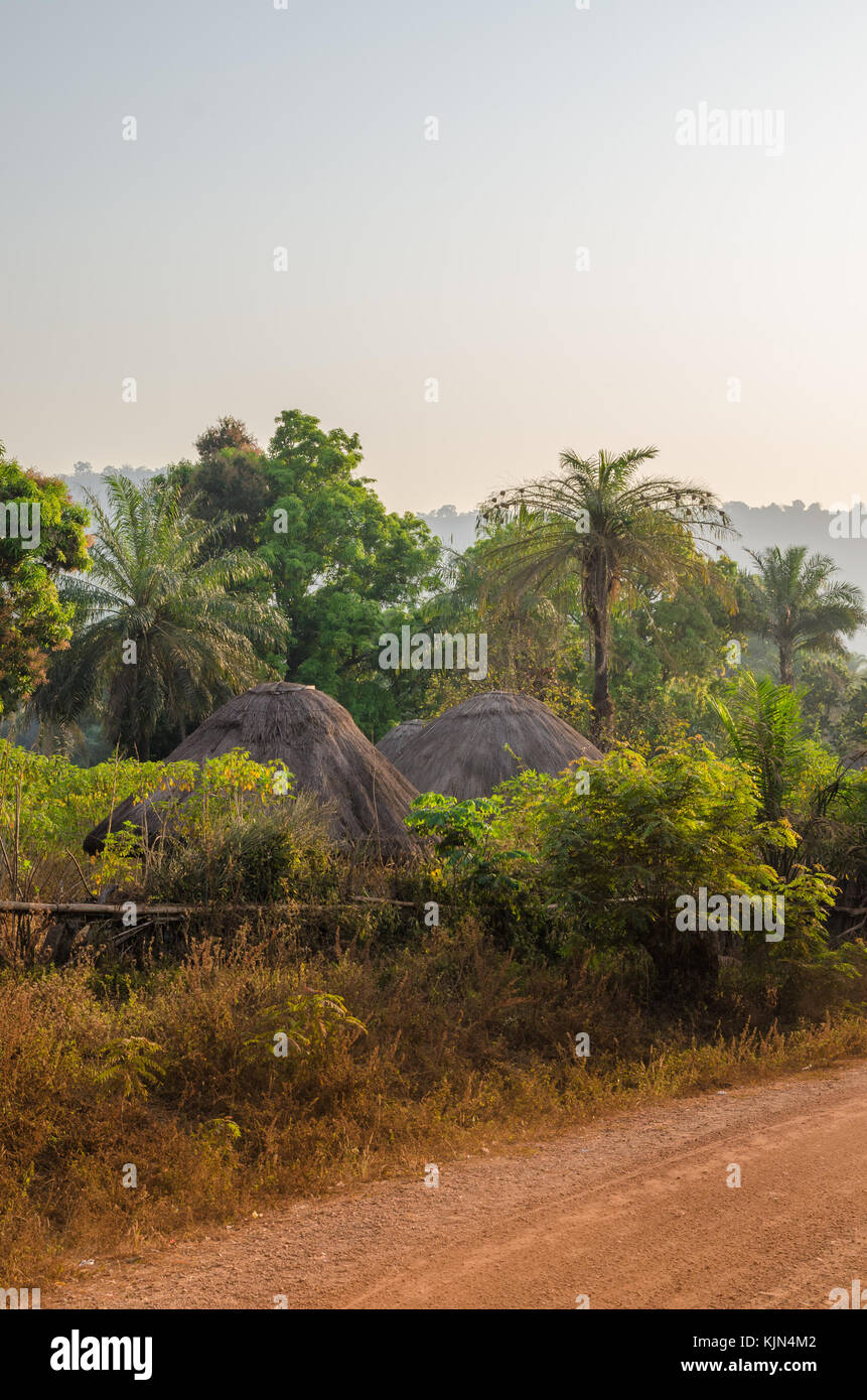 Huttes de chaume traditionnel tour de Guinée Bissau cachée parmi les arbres et palmiers de gravier pendant le coucher du soleil, l'Afrique de l'Ouest Banque D'Images