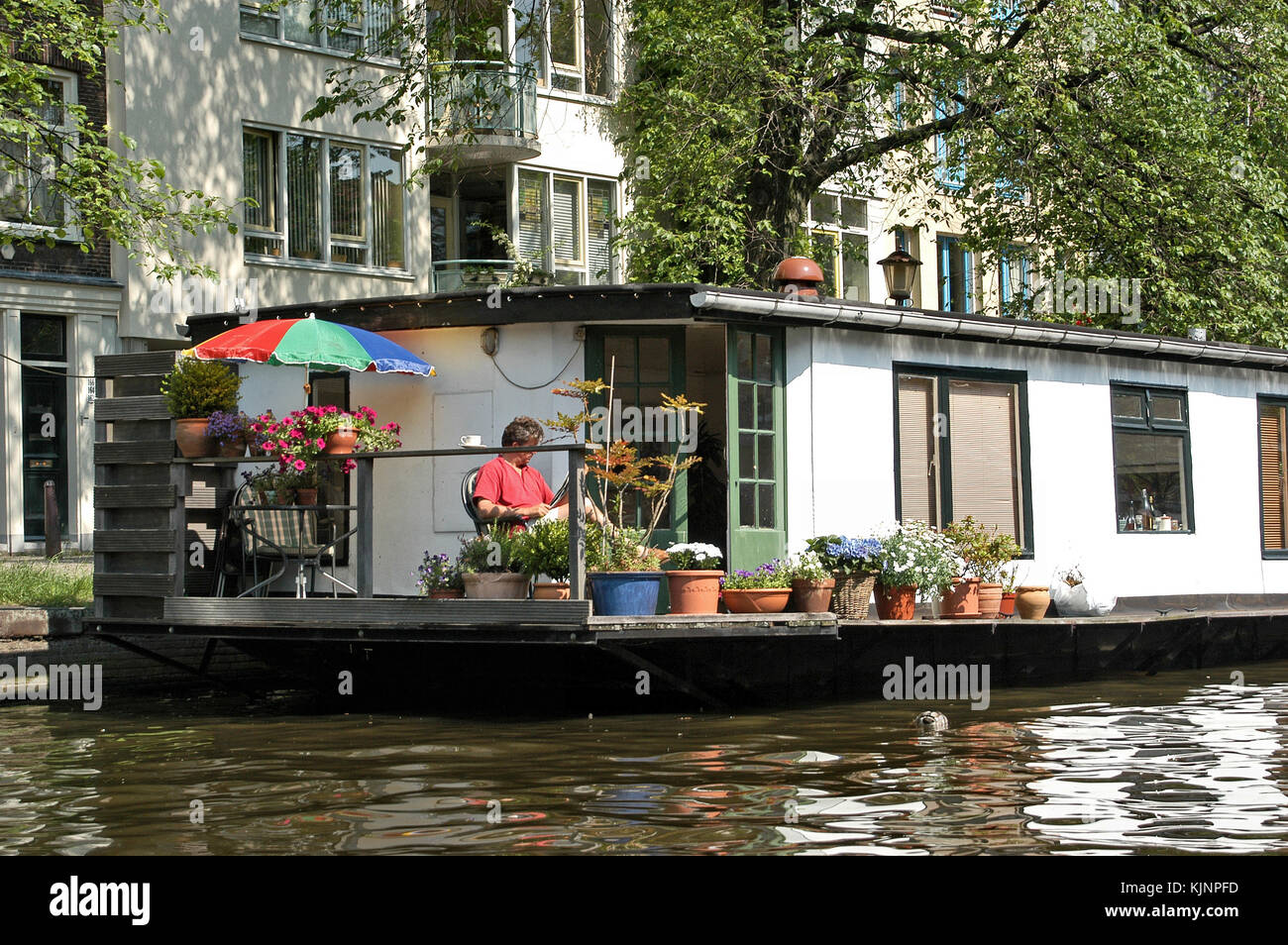 Homme se relaxant sur une péniche dans un canal à Amsterdam, aux pays-Bas Banque D'Images