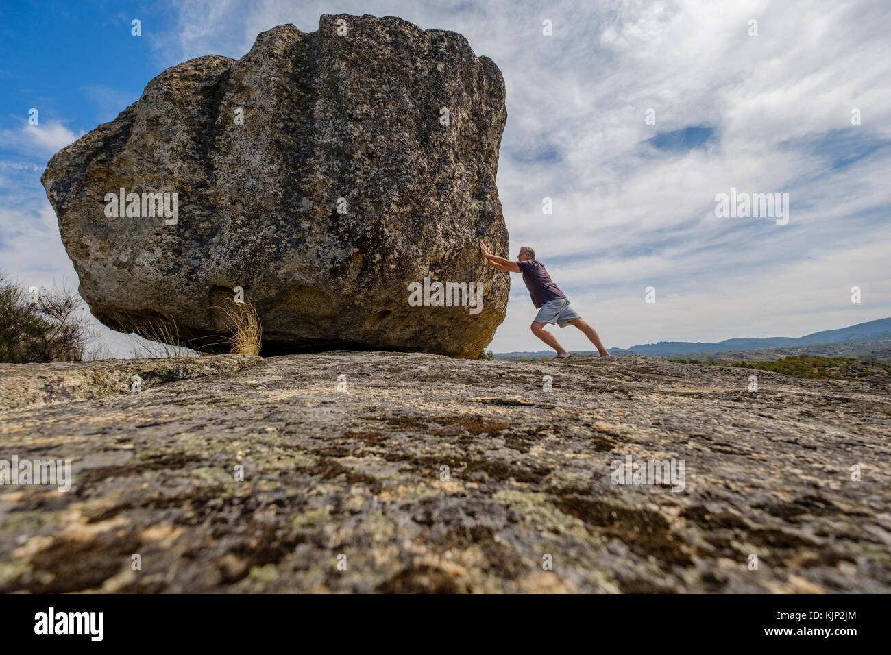 L'homme en poussant un rocher sur un rocher Banque D'Images