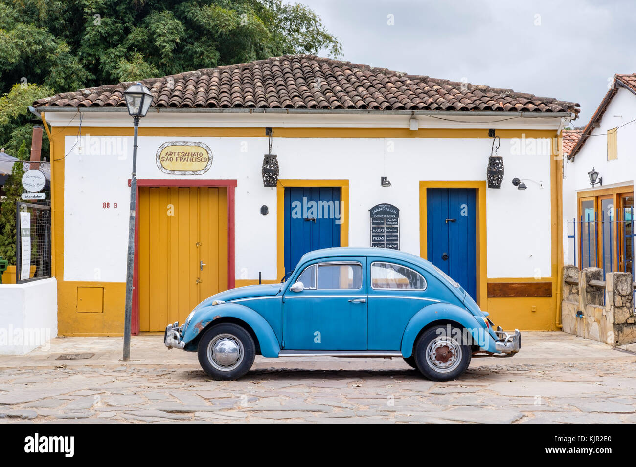 Maison coloniale jaune, bleu coccinelle Volkswagen, rue pavée, Tiradentes, Minas Gerais, Brésil. Banque D'Images