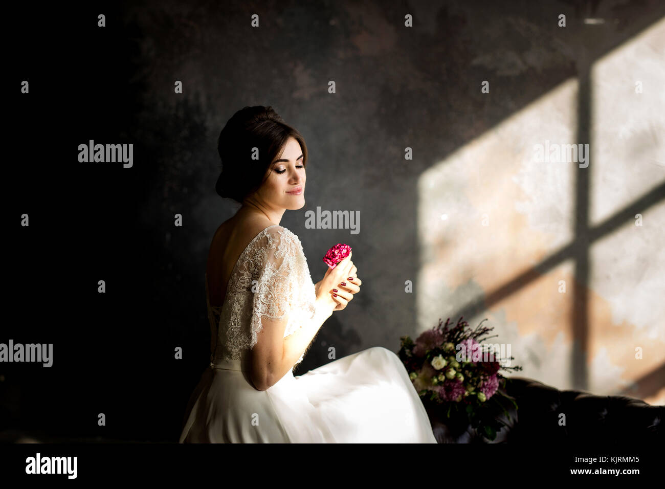 Belle robe de mariée assis sur une chaise à l'intérieur dans dark studio intérieur comme à la maison. Banque D'Images