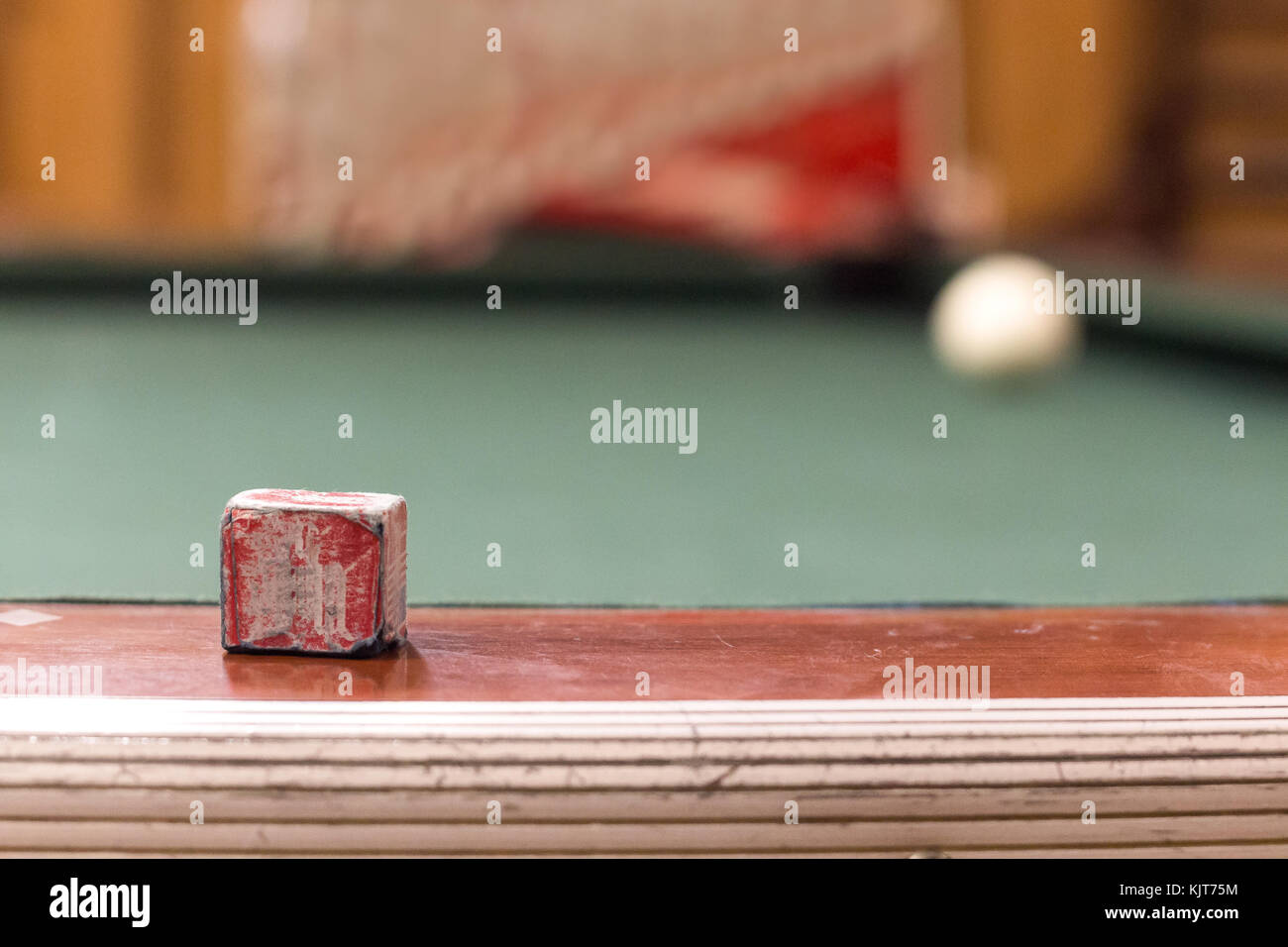 Une piscine utilisée craie placé sur le côté d'un vintage table de billard avec la boule blanche sur le coin en arrière-plan. Banque D'Images