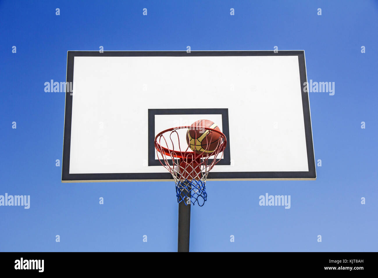 Balle de basket-ball le panier dans le fond de ciel bleu Banque D'Images