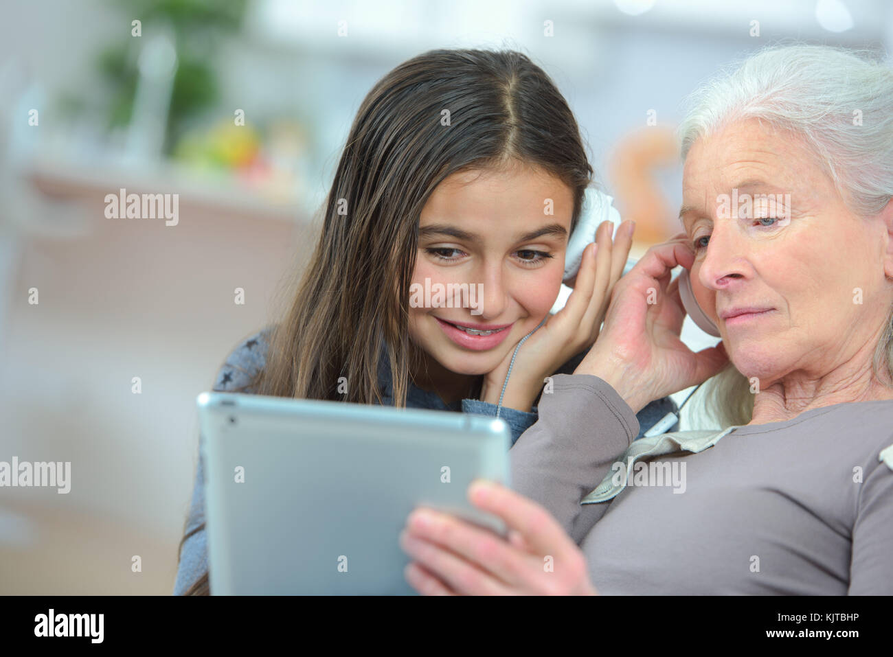 Petite fille heureuse et grand-mère jouant avec une tablette Banque D'Images