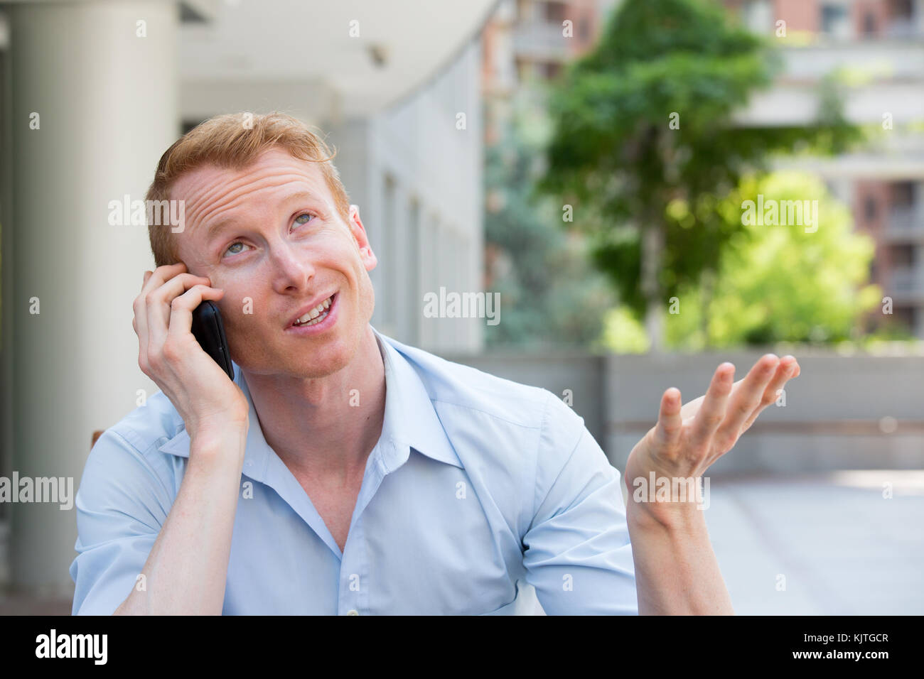 Closeup portrait, jeune homme contrarié, frustré, énervé par quelqu'un parler sur son téléphone mobile, de mauvaises nouvelles, isolé à l'extérieur à l'extérieur de l'arrière-plan. lo Banque D'Images