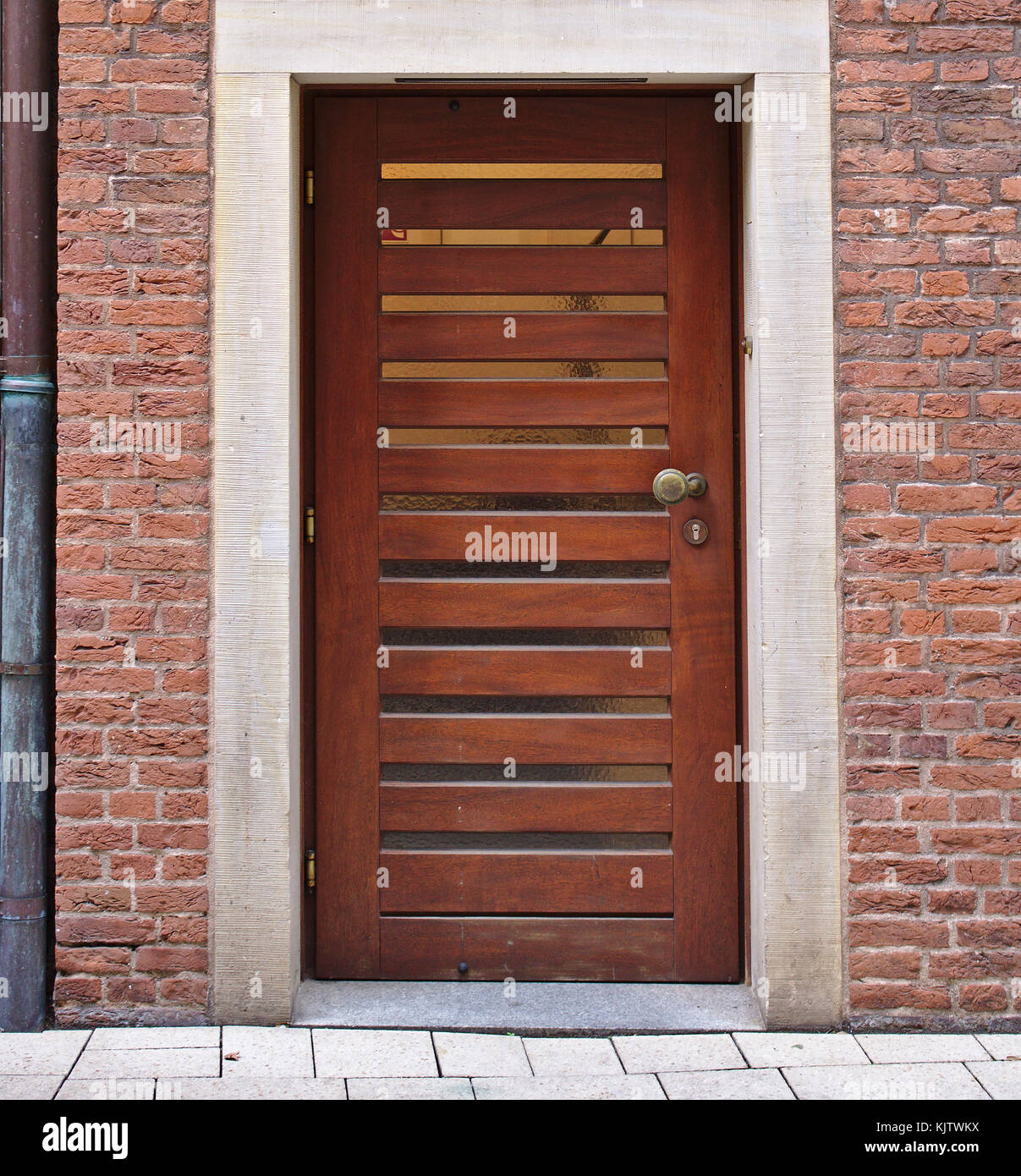 Porte en bois moderne en brique rouge avec des volets de fenêtre horizontale étroite et descente Banque D'Images
