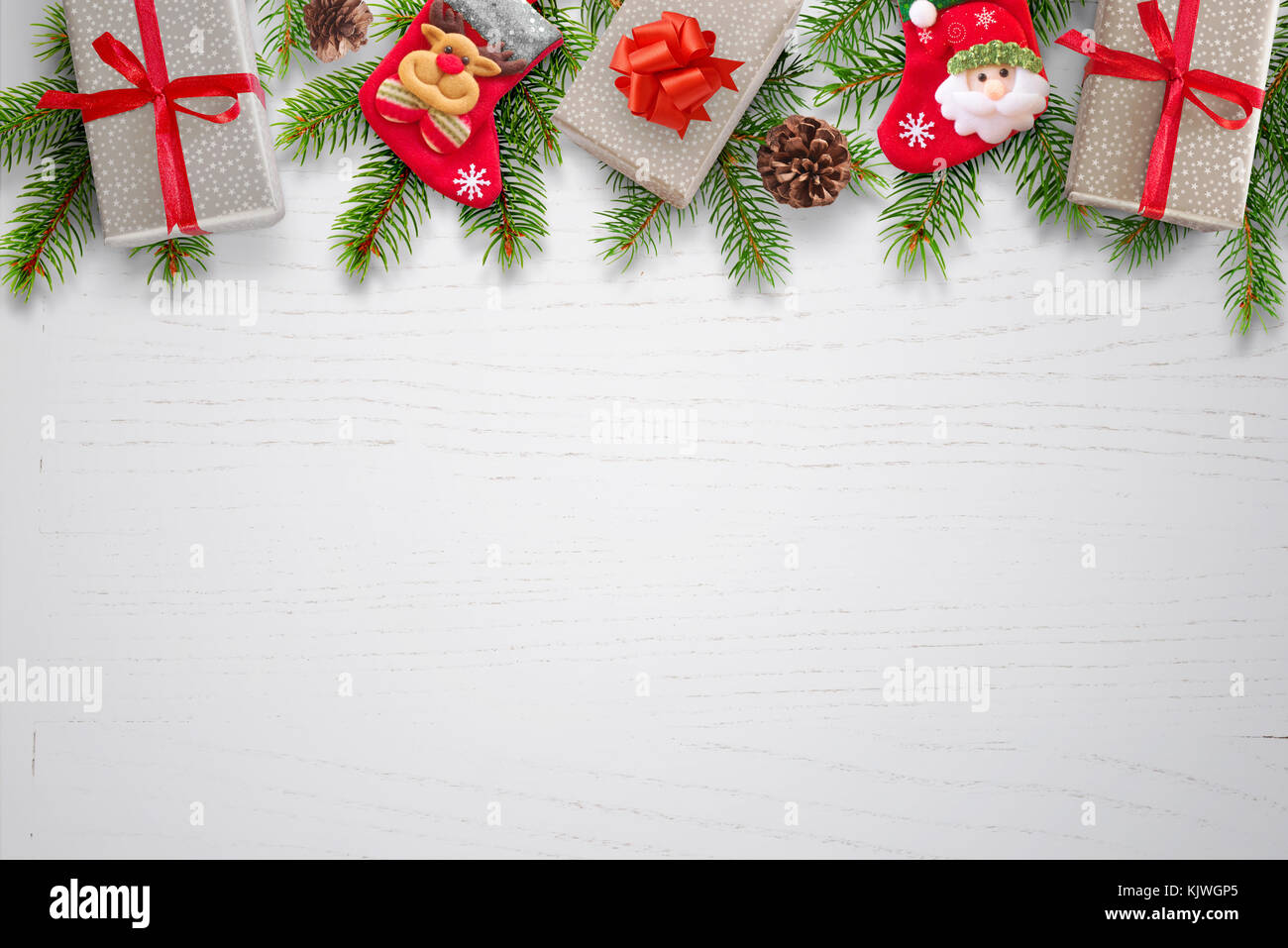 Fond de Noël avec des cadeaux, des chaussettes, des pommes de pin et branches de sapin sur le dessus de table en bois blanc propre. avec l'espace pour le texte. vue d'en haut. Banque D'Images