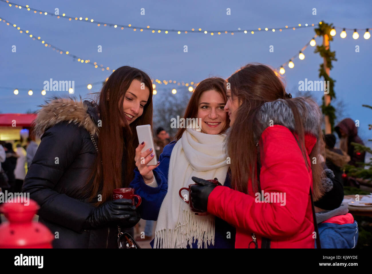 Trois jeunes femme faisant des photos à la marché de Noël Banque D'Images