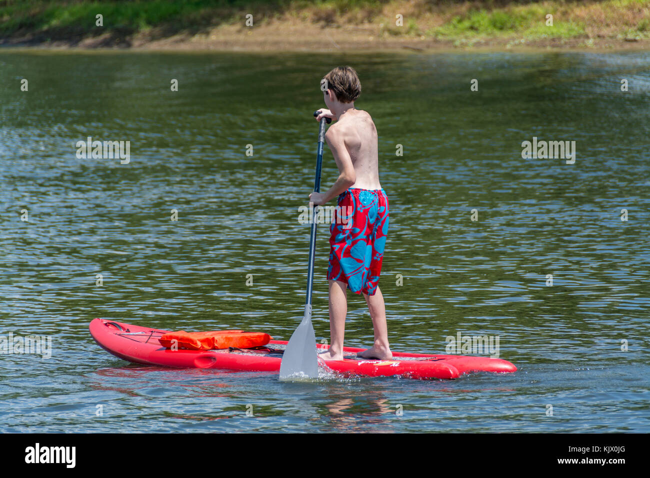 Jeune garçon sur un paddle board sur un petit lac Banque D'Images