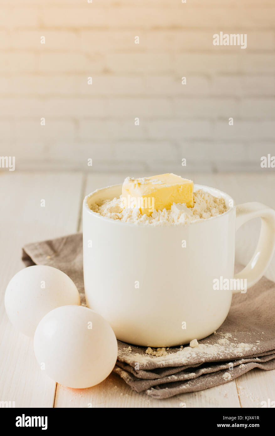 Tasse de farine blanche et de morceau de beurre et d'œufs selective focus Banque D'Images