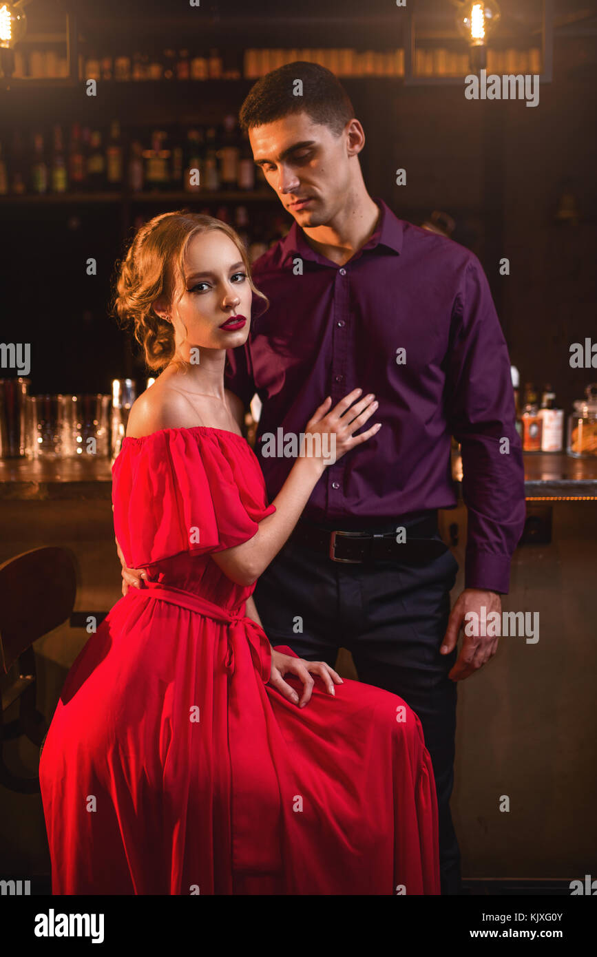 Belle femme en robe rouge avec son homme contre comptoir bar. date en boîte  de nuit, l'amour en couple attrayant pub Photo Stock - Alamy