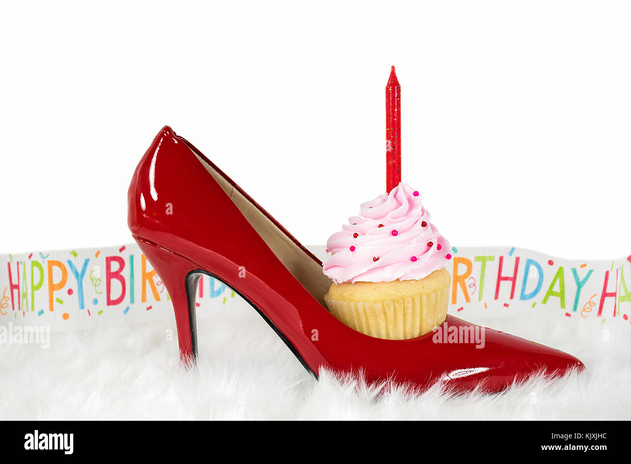 Chaussure haut talon rouge sur la fourrure avec anniversaire cupcake en bannière du parti et Banque D'Images