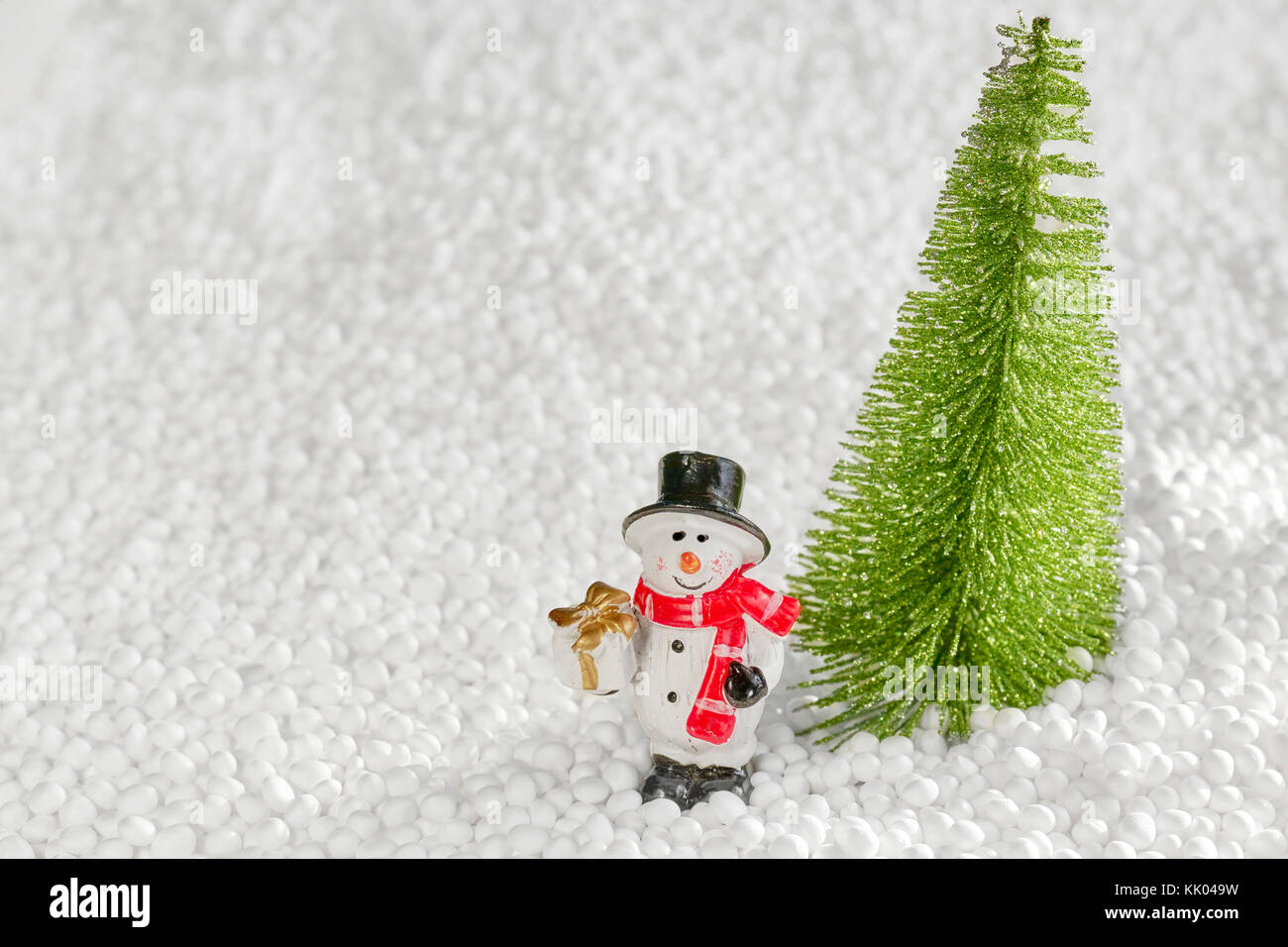 Bonhomme de neige miniature avec un cadeau s'en tient à un arbre de Noël, profondeur de champ, l'espace pour le texte. Banque D'Images