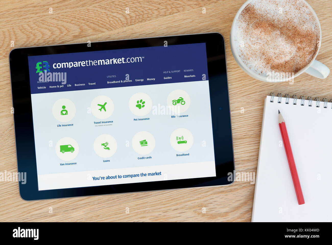 Un homme regarde les comparer le marché site sur son iPad tablet device, tourné contre une table en bois page contexte (usage éditorial uniquement) Banque D'Images