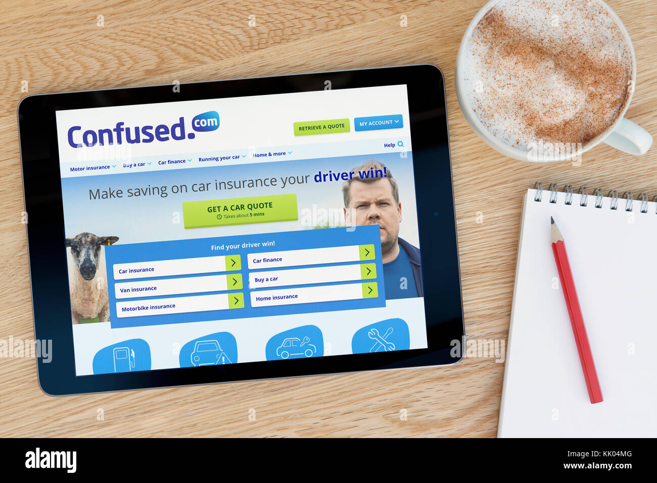 Un homme regarde le site Confused.com sur son iPad tablet device, tourné contre une table en bois page contexte (usage éditorial uniquement) Banque D'Images