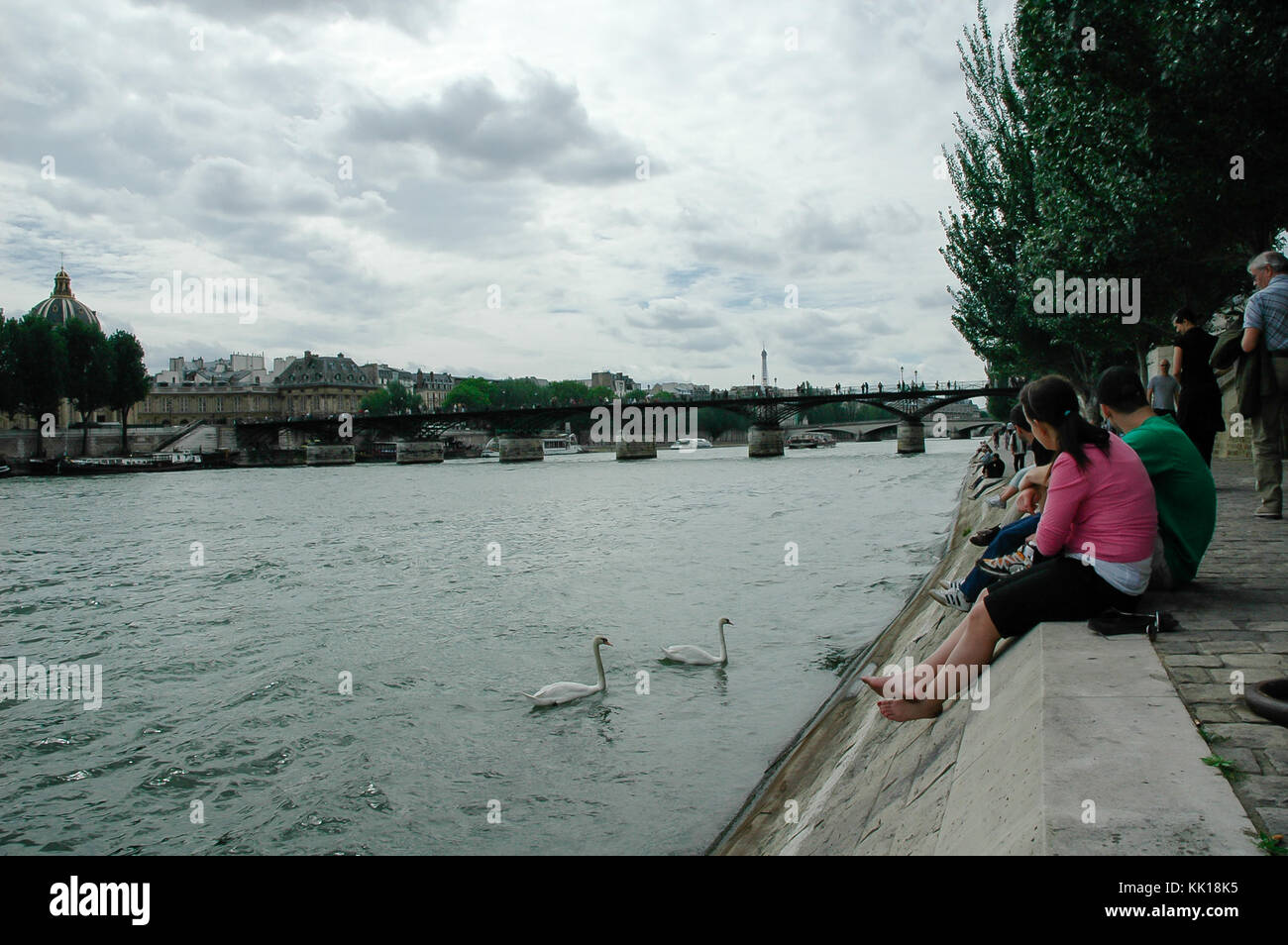 Les touristes assis sur les bords de Seine avec les piétons cygnes alimentation bridge pont des arts dans l'arrière-plan, Paris, France Banque D'Images