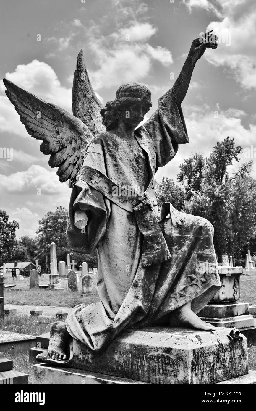 Cet ange s'agenouille au sommet d'un mémorial à l'épitaphe "Il est semé en faiblesse, il est relevé au pouvoir." Banque D'Images Cet ange s'agenouille au sommet d'un mémorial à l'épitaphe "Il est semé en faiblesse, il est relevé au pouvoir." Banque D'Images
