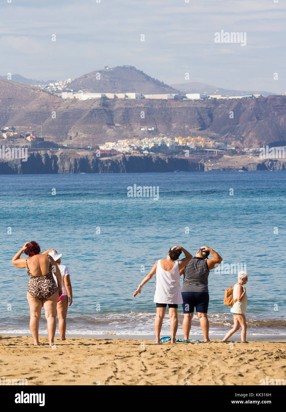 Les femmes âgées locales passent par leur routine à leur cours quotidien de maintien de la forme sur la plage en Espagne. Banque D'Images