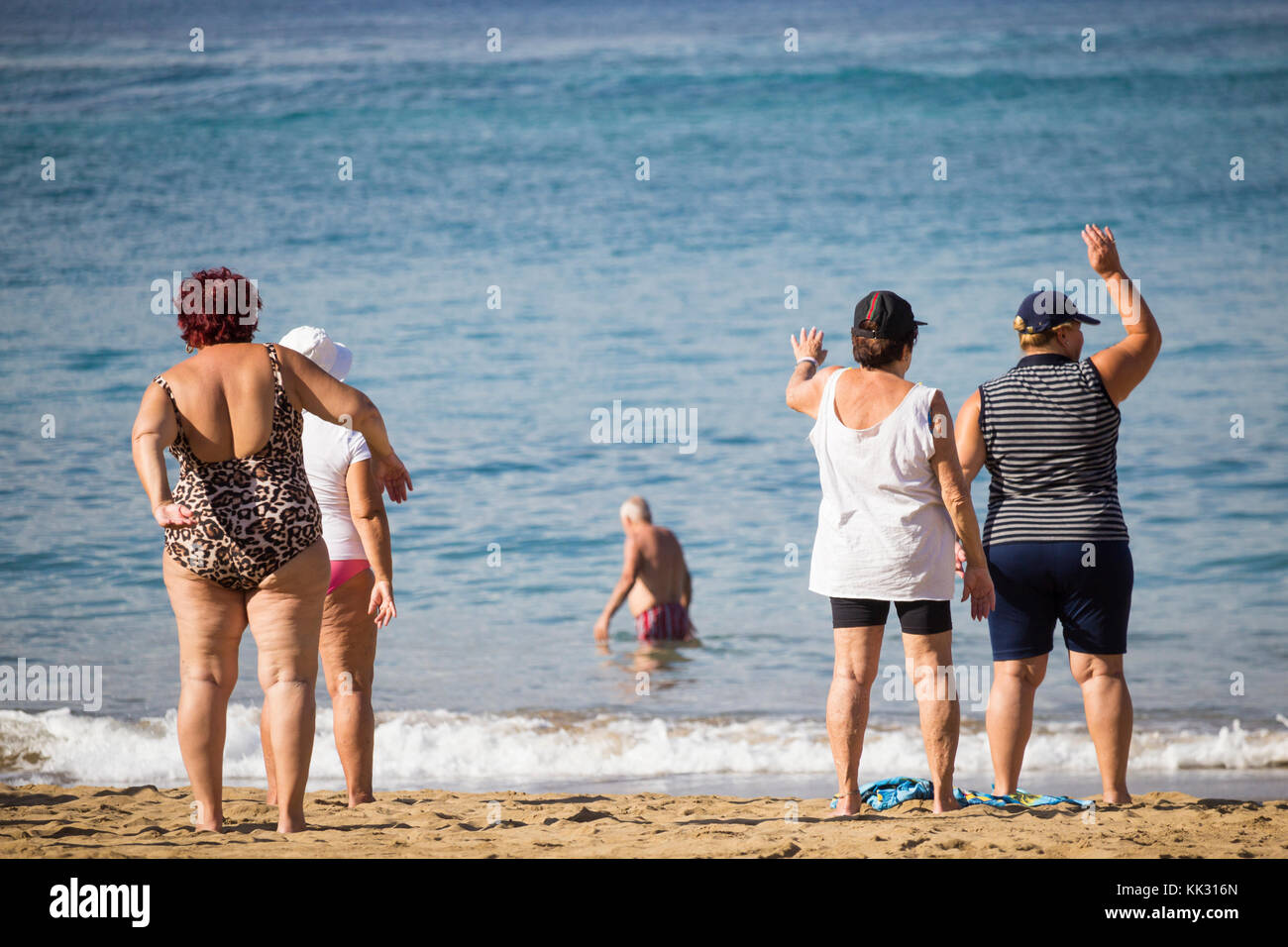 Les femmes âgées locales passent par leur routine à leur cours quotidien de maintien de la forme sur la plage en Espagne. Banque D'Images