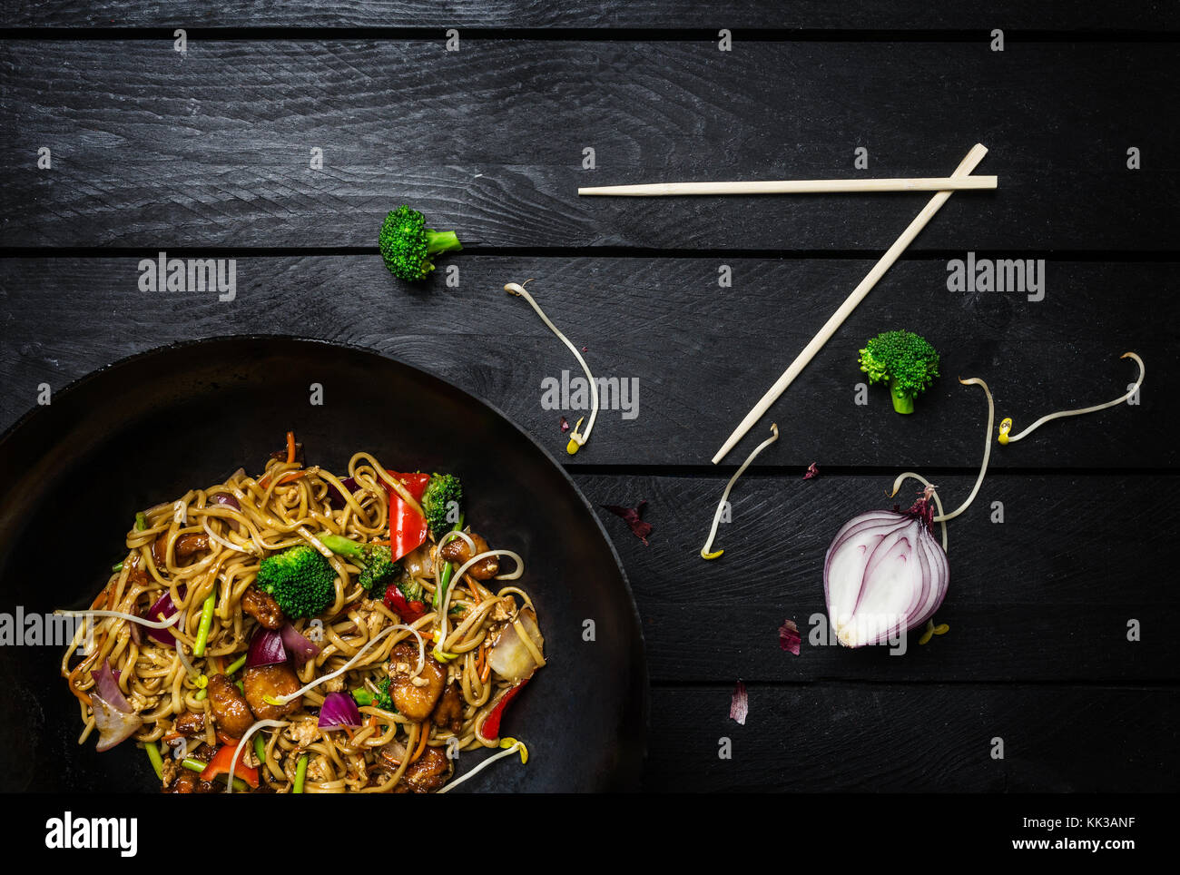 Udon nouilles sauté au poulet et légumes au wok casserole sur fond de bois noir avec des baguettes. Vue de dessus Banque D'Images