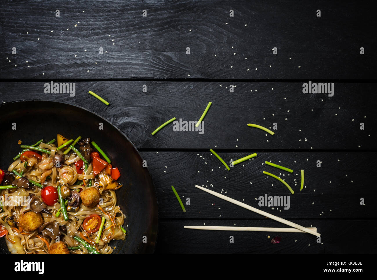 Faire sauter les nouilles Udon avec des fruits de mer et légumes en wok casserole sur fond de bois noir. avec un fort pour les nouilles Banque D'Images