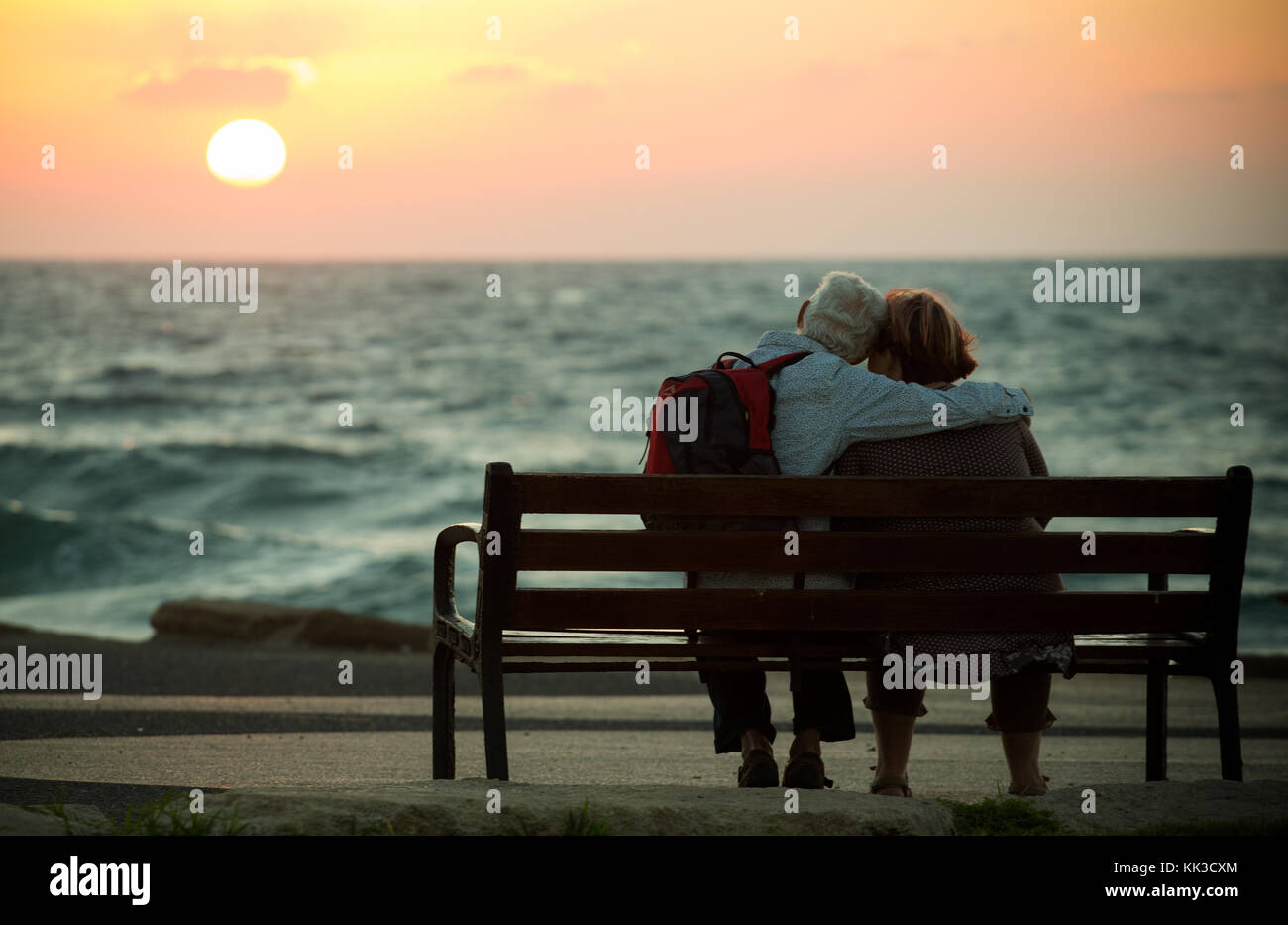 Vieux couple romantique sur un banc à regarder le coucher du soleil sur la mer méditerranée à Tel Aviv. Banque D'Images