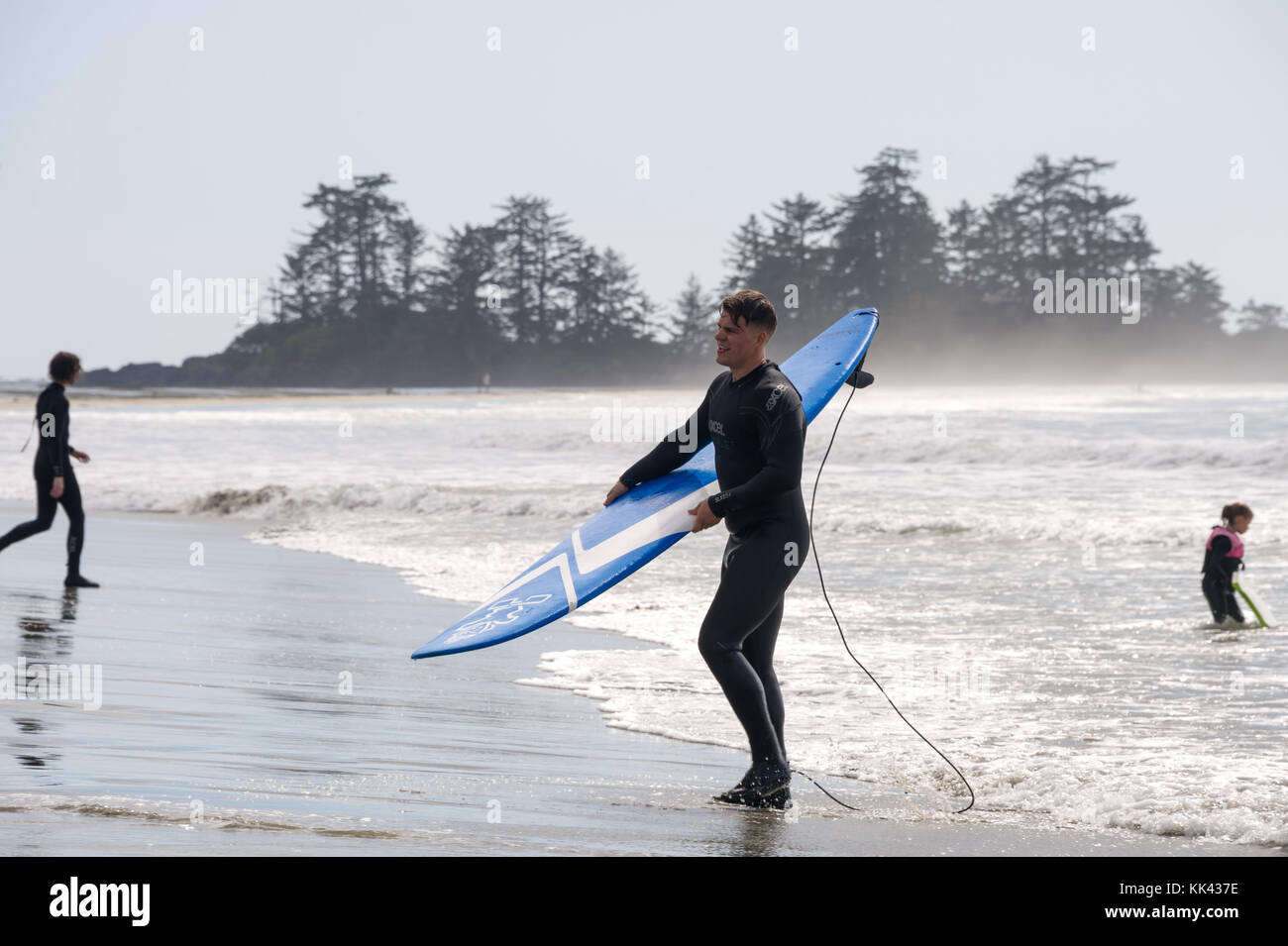 Plage de Chesterman près de Tofino, C.-B., Canada (septembre 2017) - surfeur masculin tenant une planche à voile. Banque D'Images