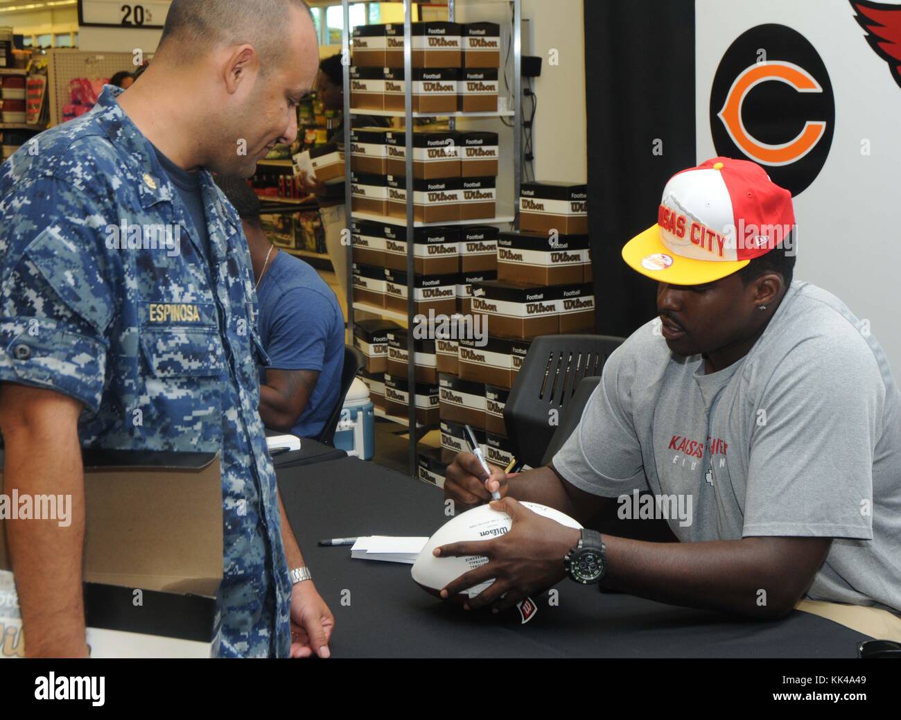 David Mims, Left Tackle for the Kansas City Chiefs, autographe un ballon de football pour le Chief Aviation Structural Mechanic Gilberto Espinosa lors d'une visite à la Norfolk Navy Exchange, Norfolk, Virginie, 2012. Image avec la permission du Matelot de 1re classe Lacordrick Wilson/US Navy. Banque D'Images