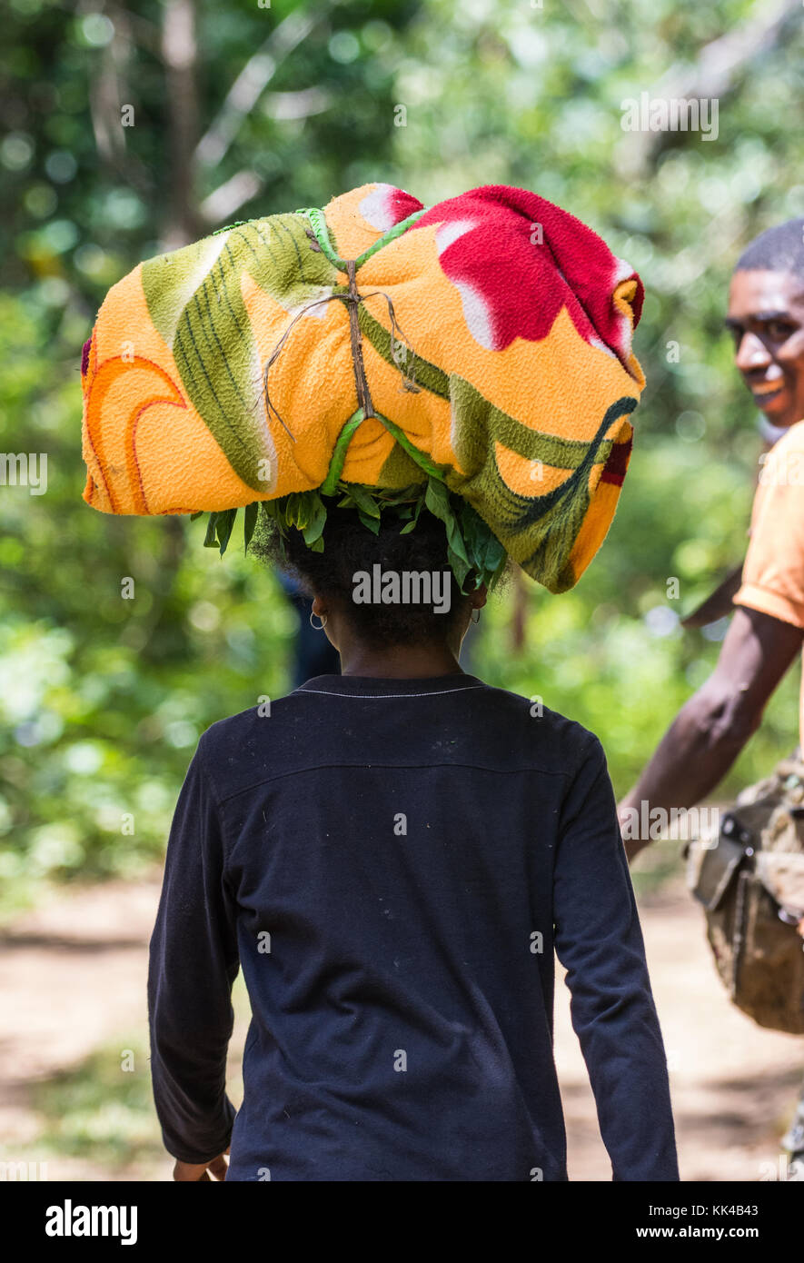 Une femme malgache billet sur route avec des bagages sur le dessus de sa tête. Madagascar, Afrique. Banque D'Images