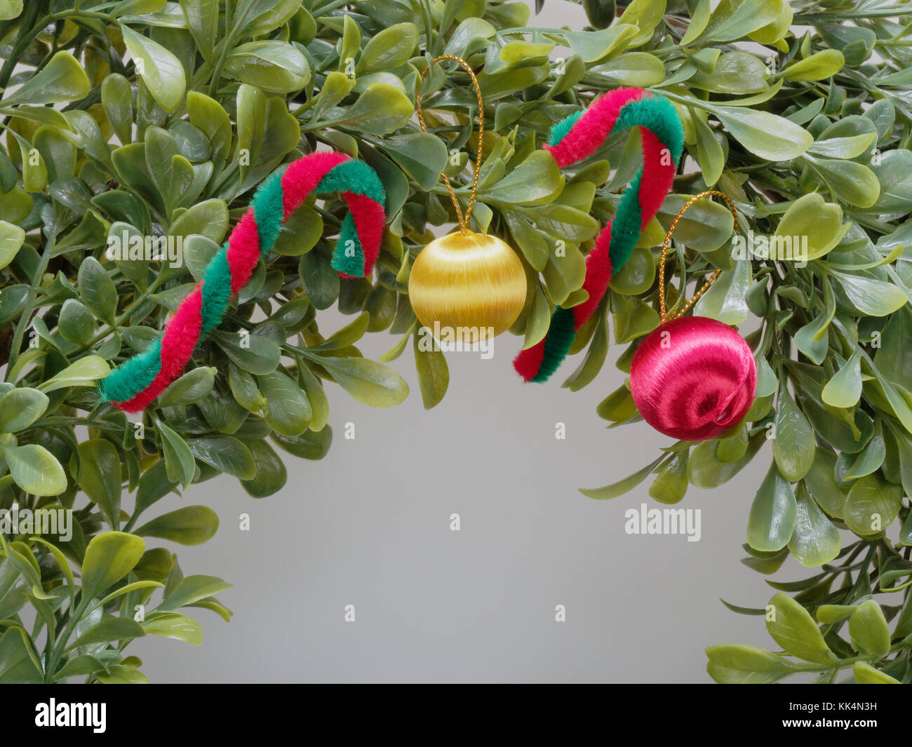 Couronne de Noël ou garland fait par feuille en plastique décorées en rouge et en canne blanche et jaune et rouge apple en close up isolé sur fond blanc Banque D'Images