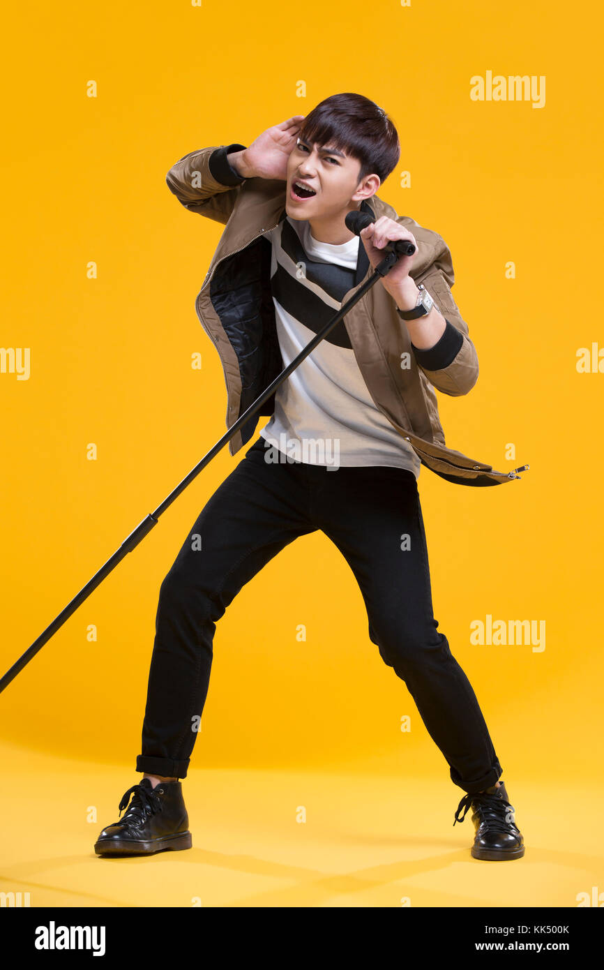 Cheerful young Chinese man singing with microphone Banque D'Images