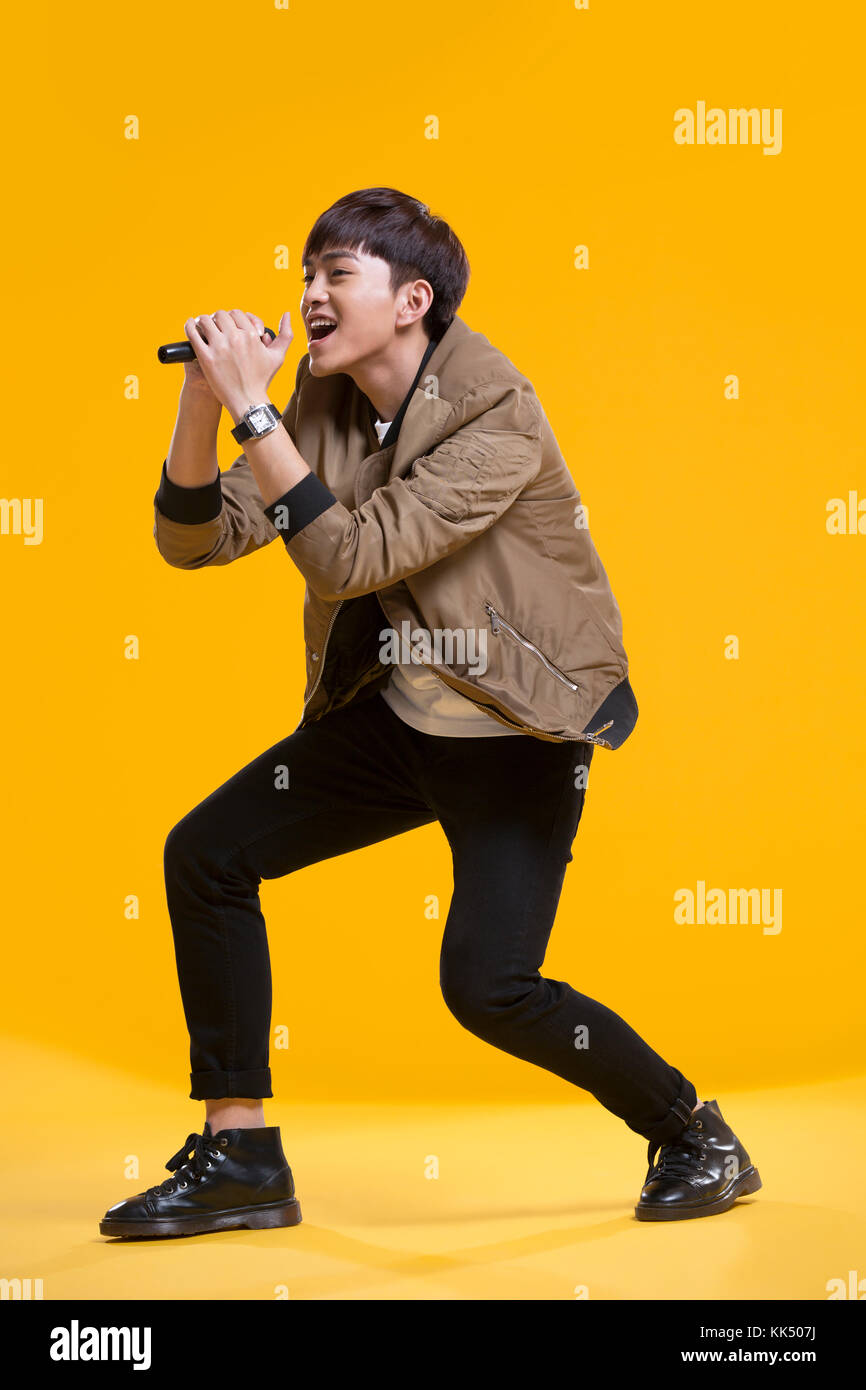 Cheerful young Chinese man singing with microphone Banque D'Images