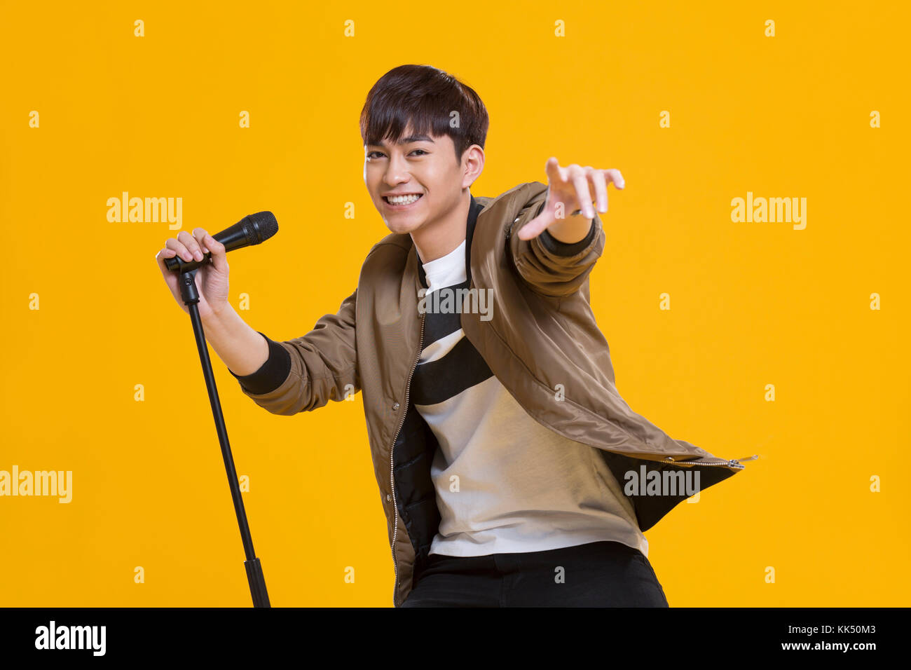 Cheerful young Chinese man singing with microphone Banque D'Images