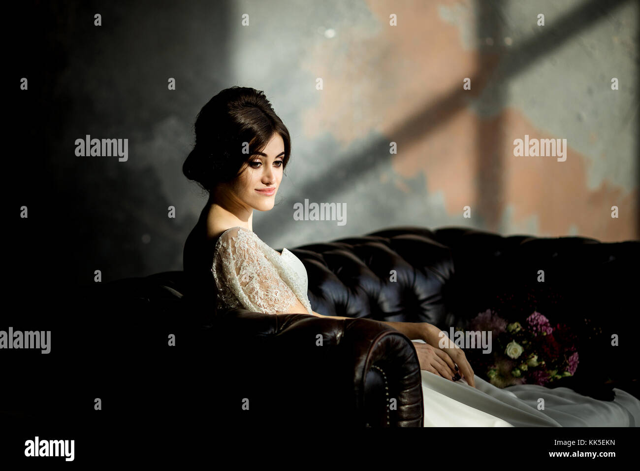Belle robe de mariée assis sur une chaise à l'intérieur dans dark studio intérieur comme à la maison. Banque D'Images
