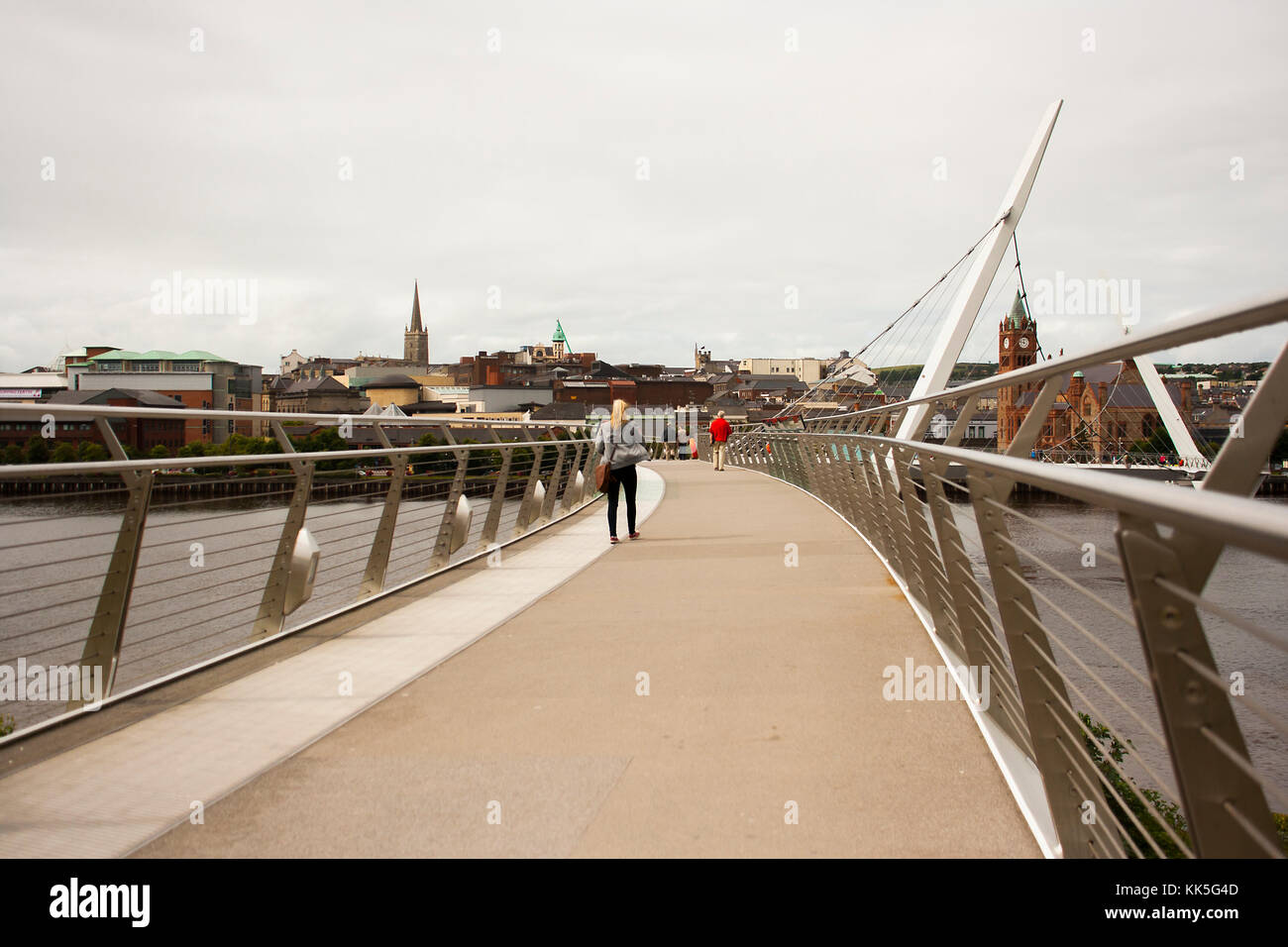 Piétons traversant le légendaire pont de la paix au-dessus de la rivière Foyle dans la ville de Londonderry en Irlande du Nord Banque D'Images